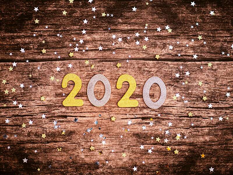 The numbers "2020" in gold and silver glitter are surrounded by scattered stars on a wooden surface, celebrating the New Year inside WebBox's brand new HQ.