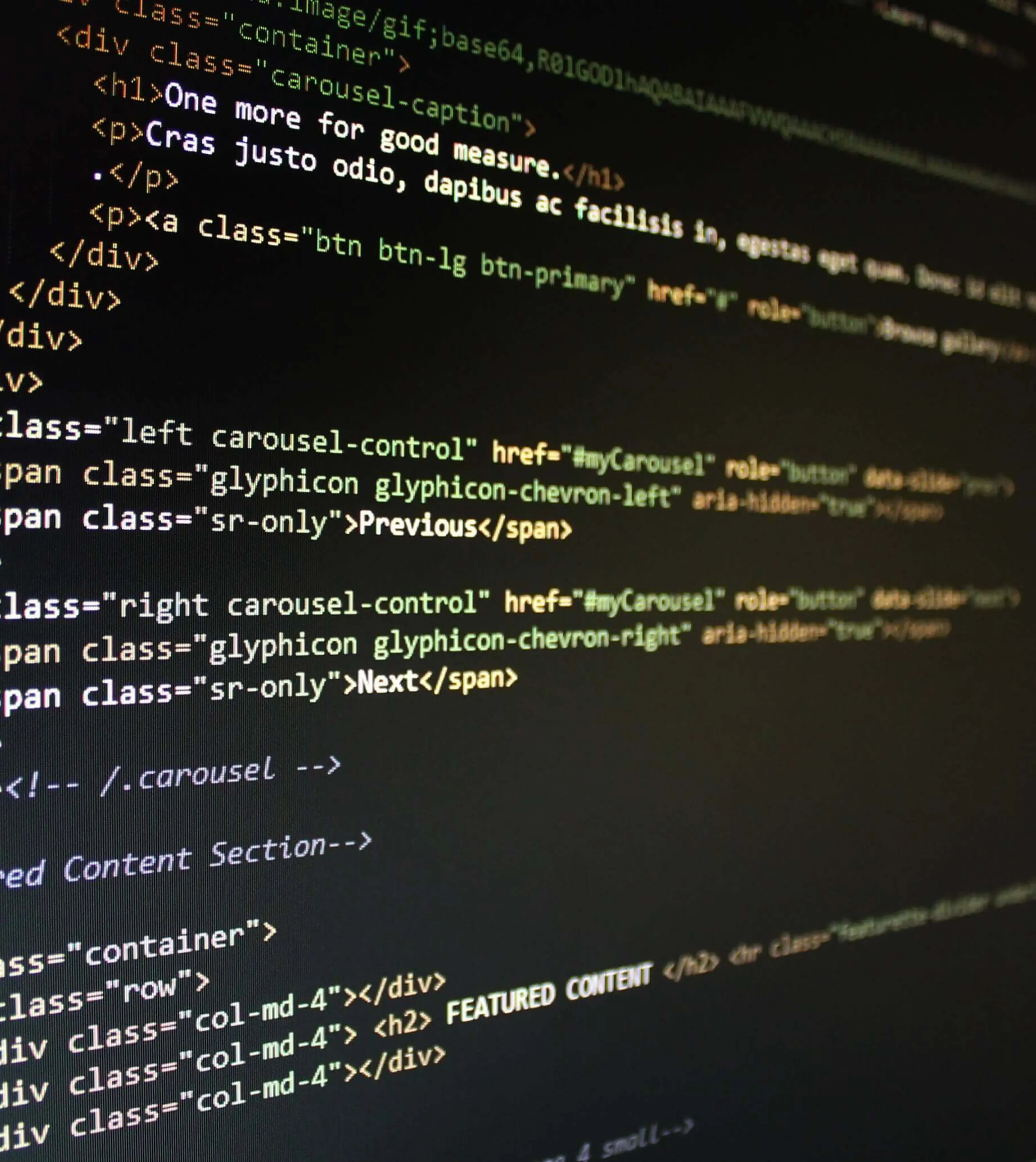 A close-up of a computer screen displaying HTML and CSS code, featuring tags, attributes, and text content. The screen is predominantly black with colorful syntax highlighting.