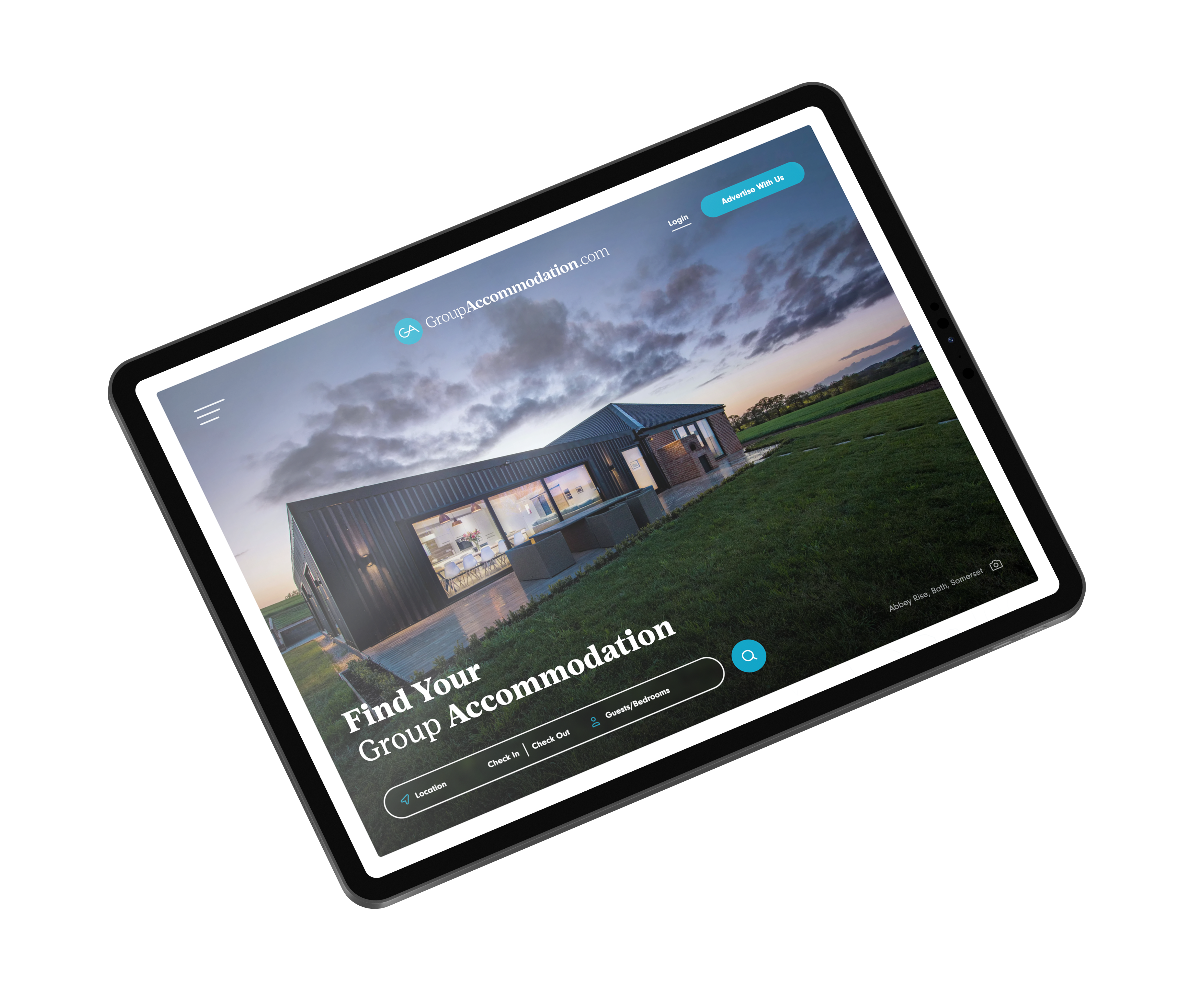 Tablet displaying a website for group accommodation, featuring a modern house in a spacious green landscape at sunset. The website prompts users to find group stays.